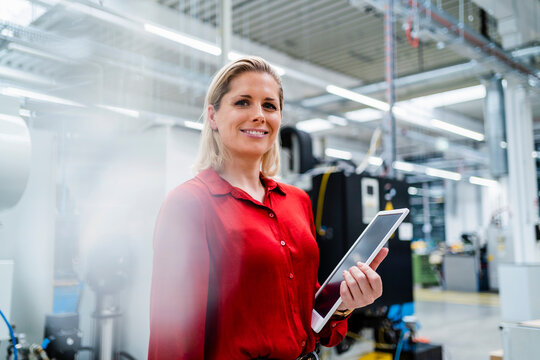 Businesswoman wearing red shirt holding tablet PC in industry