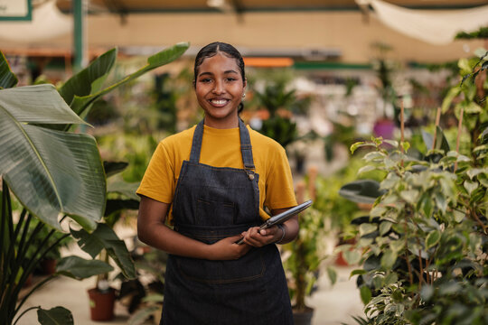 Garden center worker smiling with tablet among plants