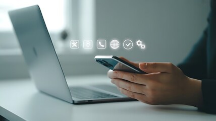 Person using smartphone with digital icons overlayed near a laptop
