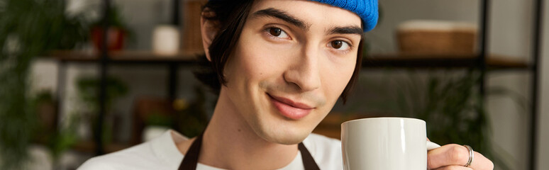 Handsome young man enjoys a moment with a mug while transplanting plants in a cozy studio