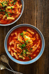 Tomato soup with chicken thigh and noodles on wooden table