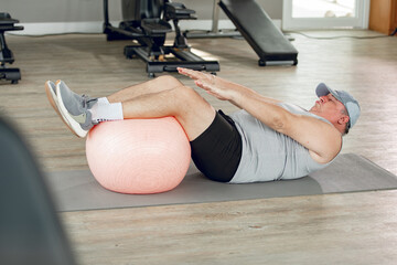 Man at the gym doing exercises for his abs with a Swiss ball