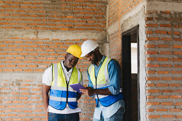Two engineers in safety gear inspecting a building under construction. black engineers inspect ceiling infrastructure at a construction site