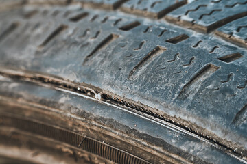 Worn-out car tire with visible damage and bald spots