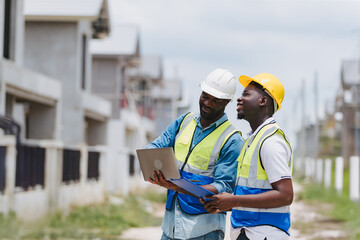 Two engineers in safety gear inspecting a building under construction. black engineers inspect...