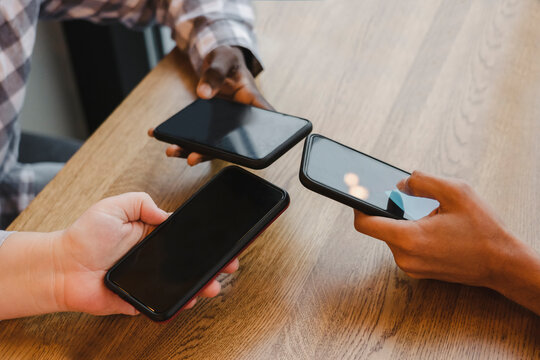 Friends with mobile phones at table in cafe