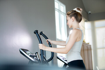 female athlete exercising on stationary bike during her spinning class in a gym. Exercise bike...