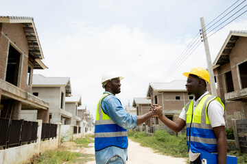 workers at construction site, young engineer manager and worker handshaking at construction site ....