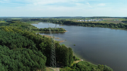 Obraz premium Transmission tower near peaceful forest lake