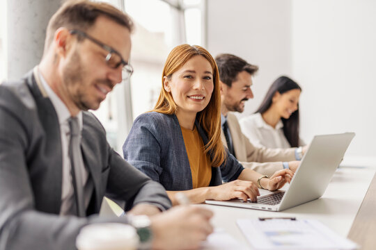 Selective focus on smiling businesswoman typing on a laptop and sitting with her leadership team at conference room.