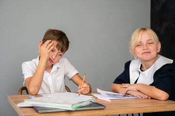 Boy Girl Homework - Boy doing homework at a table while girl looks on.