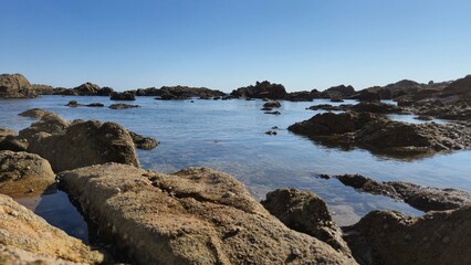 The Gondarem Beach in Foz do Douro, Porto, Portugal. Calm tide over rocky coastline and coarse sand, perfect for resting and relaxing in the summer by the Atlantic shore.