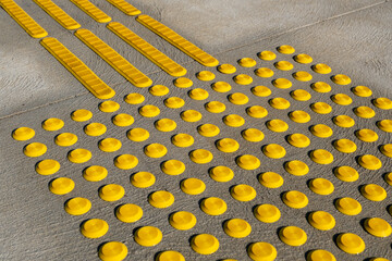 Yellow tactile ground surface indicators (TGSIs) installed on a concrete pavement in an Australian...