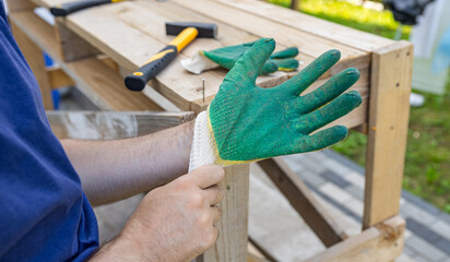 A builder puts on construction gloves to protect his hands. A man puts on work gloves at a...