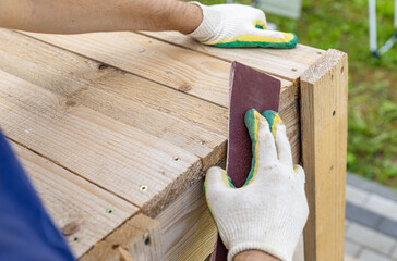 Tools for sanding wood. Carpenter sanding wooden plank on table, closeup. Sanding wood with...