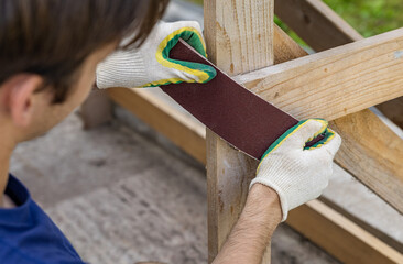 Tools for sanding wood. Carpenter sanding wooden plank on table, closeup. Sanding wood with...