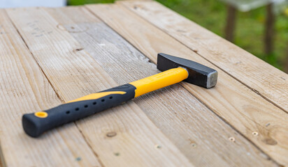 Top view of a hammer lying on a wooden surface. Space for text and copy. Construction site.