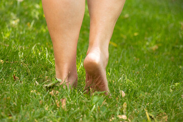 Bare feet of an elderly woman on the grass in the summer in a park in Ukraine
