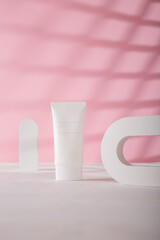 White cosmetics tube mockup template, concrete decorative arch on pink background. Unbranded beauty product, no label. Advertising banner, copy space