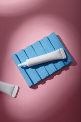 Two white narrow unbranded cosmetics tubes mockup on pink background, harsh light with shadows. Beauty product template. Copy space, top view, flat lay
