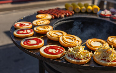 Close-up view of a flat top grill, showcasing the final stages of assembling burgers. Toasted buns...