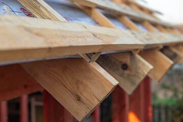  lose-up of a wooden roof frame during construction. The wooden planks are arranged in a grid...