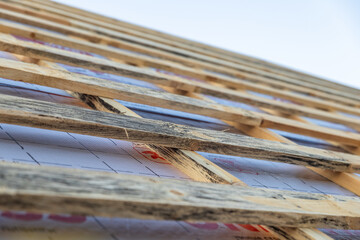  lose-up of a wooden roof frame during construction. The wooden planks are arranged in a grid...