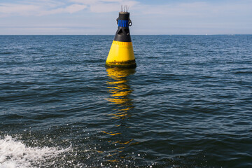 A North Cardinal Mark, a yellow and black navigational buoy, floating in the open blue sea to provide safety and guidance for passing ships.
