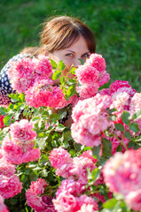 Naklejka premium Beautiful young woman in a polka dot dress with roses, in a park on a sunny day