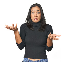 Simple portrait of a young Latina doubting and shrugging shoulders in questioning gesture.