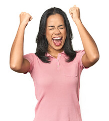 Simple portrait of a young Latina raising fist after a victory, winner concept.