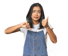 Simple portrait of a young Latina showing thumbs up and thumbs down, difficult choose concept