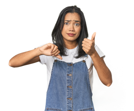 Simple portrait of a young Latina showing thumbs up and thumbs down, difficult choose concept - Powered by Adobe