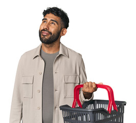 Young Hispanic man holding a shopping basket in studio