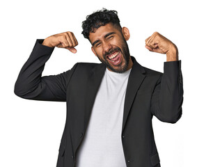Hispanic businessman in suit in studio showing strength gesture with arms, symbol of feminine power