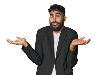 Hispanic businessman in suit in studio doubting and shrugging shoulders in questioning gesture.