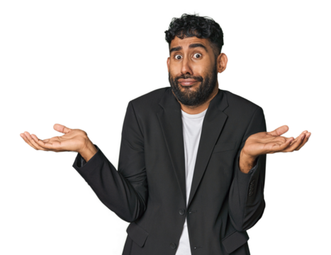 Hispanic businessman in suit in studio doubting and shrugging shoulders in questioning gesture.