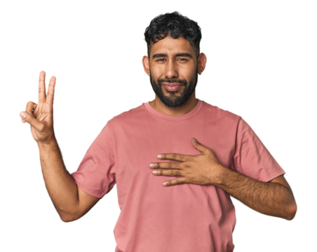 Young Hispanic man isolated taking an oath, putting hand on chest.
