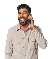 Young Hispanic man talking on mobile phone happily in studio