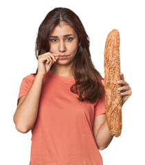 Middle Eastern woman holding bread loaf with fingers on lips keeping a secret.