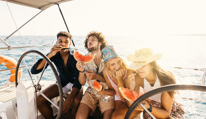 Group of friends eating slices of refreshing watermelon while sailing on a yacht during summer...