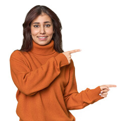 Middle Eastern woman in studio shocked pointing with index fingers to a copy space.