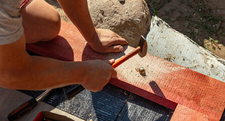 A person skillfully positions a nail against a piece of wood, preparing for a precise hammering...