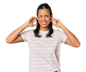 Young Filipina woman covering ears with fingers, stressed and desperate by a loudly ambient.