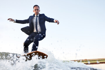 Young man surfer in classic suit rides on the wave. Happy clerk escaped from stuffy office to take...