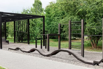 Fototapete Naturpark KRAKOW, POLAND - JULY 10, 2025: Wooden exercise equipment in a public park.  © agneskantaruk
