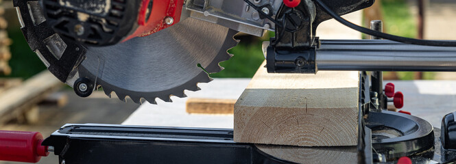 Cuts a wooden beam using a circular saw. Home furniture workshop. Work in his carpentry workshop....