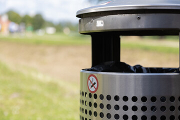 Outdoor Trash Can with Anti-Smoking Sign in a Park Setting