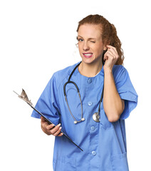Nurse with report in studio covering ears with hands.