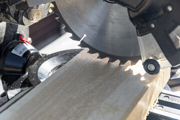 Using a miter saw to cut a piece of wood. Own carpentry workshop. Sawing a wooden board with a...